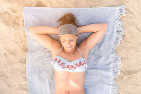 Smiling woman in swimwear sunbathing on beach