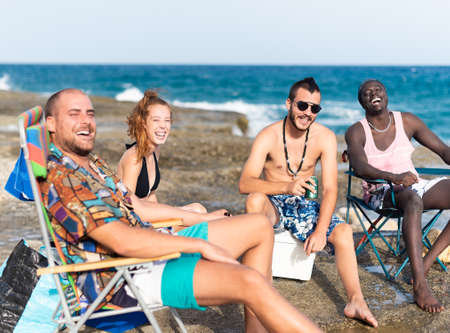 four young people sunbathing on a rocky beachの写真素材