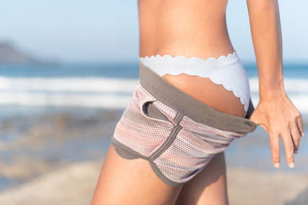 Crop slim woman in white swimwear on beach