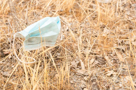 Medical mask placed on dry withered grassの写真素材