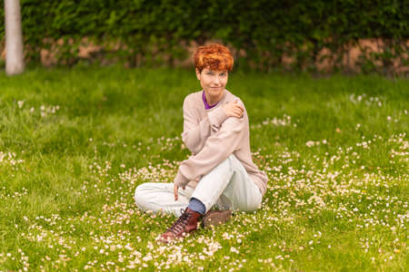 Androgynous woman resting on lawn in parkの写真素材