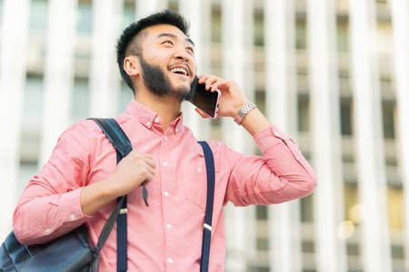 Asian man smiling while talking to the mobile outdoors