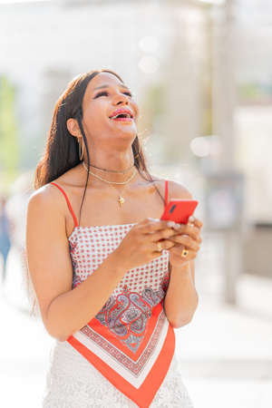 Trans woman laughing and using the mobile outdoors