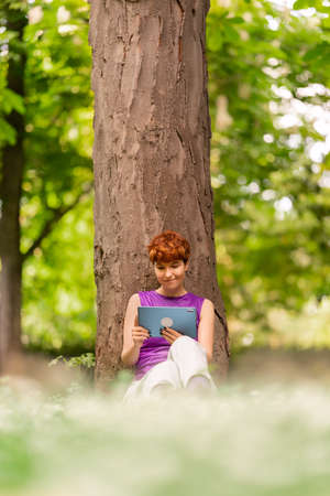 Androgynous woman watching video in a parkの写真素材