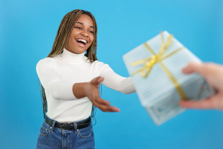 Happy casual african woman receiving a giftの写真素材