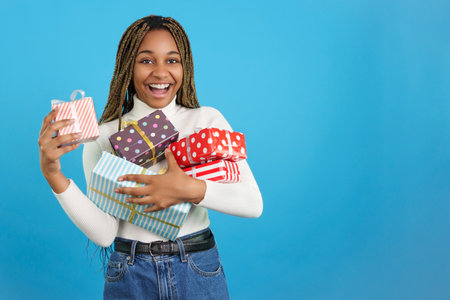 Happy african woman looking at camera while receiving many giftsの写真素材