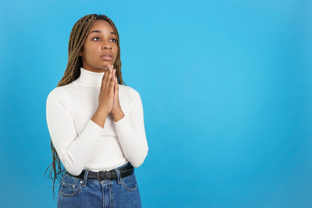Serious african woman looking up while prayingの写真素材