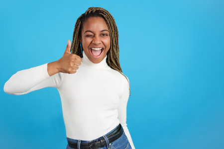 African woman winking as gesturing positively with the thumb upの写真素材