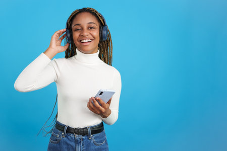 Smiling african woman looking at camera while listening to musicの写真素材