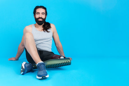 Relaxed man with a leg prosthesis sitting on the floorの写真素材