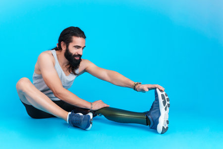 Man with a leg prosthesis sitting stretching the femoral muscleの写真素材
