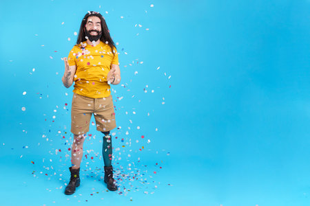 Happy man with a leg prosthesis surrounded by flying confettiの写真素材