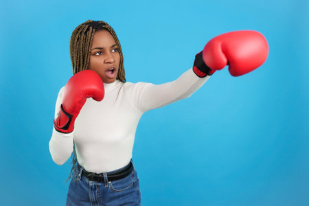 Aggressive african woman wearing boxing gloves throwing a punch