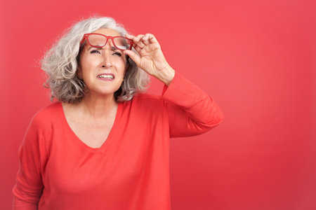 Woman lifting up her glasses to see from a distanceの写真素材