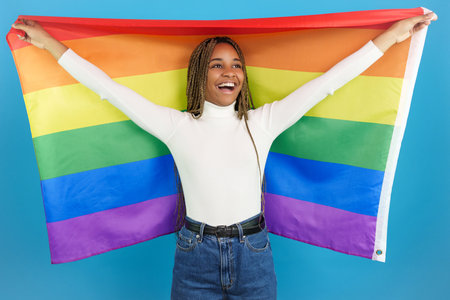 Happy african woman raising a rainbow lgbt flagの写真素材