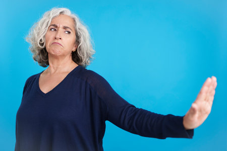 Mature woman gesturing that she wants to know nothingの写真素材