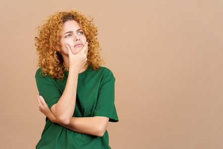 Woman gesturing and looking up with doubtful expressionの写真素材