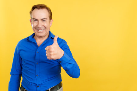 Happy mature man gesturing agreement raising a thumb upの写真素材