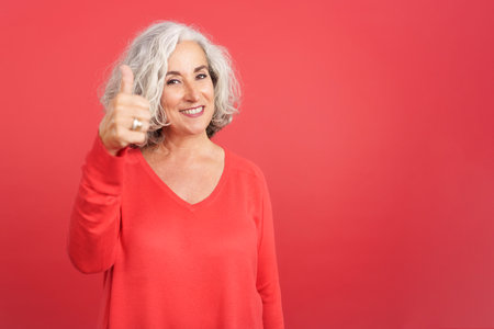 Mature woman gesturing agreement raising the thumbの写真素材