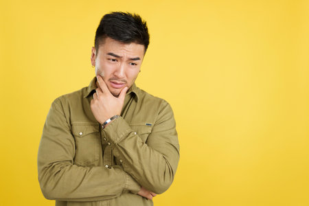Worried chinese man looking down with pensive expressionの写真素材