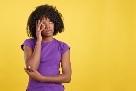 Bored woman with afro hair looking upの写真素材