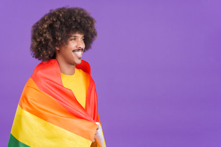 Smiling african man wrapped with a lgbt flagの写真素材