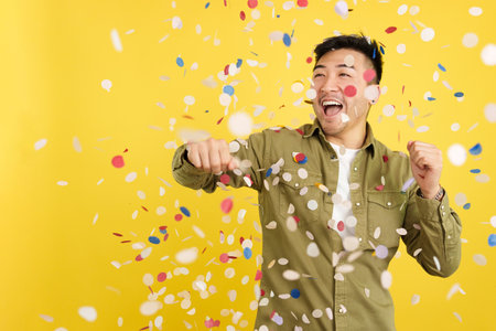 Happy chinese man surrounded by confetti flying in the airの写真素材