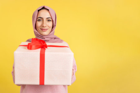 Happy muslim woman smiling at camera while giving a giftの写真素材