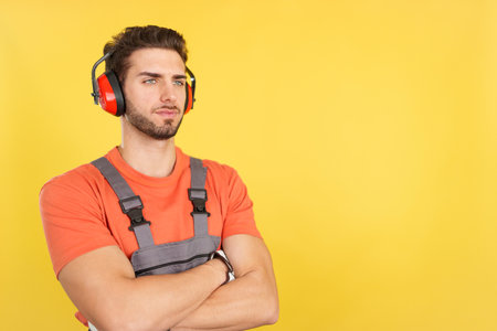 Serious worker with headphones standing looking asideの写真素材