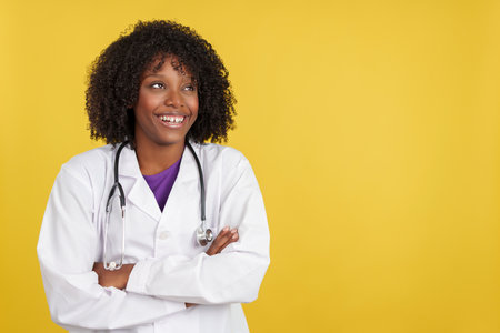 Happy doctor with afro hairstyle smiling standing with arms crossedの写真素材