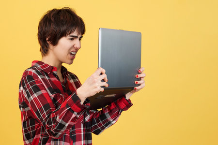 Worried androgynous person standing while using a laptopの写真素材