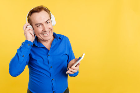 Mature man listening to music with headphones and mobileの写真素材