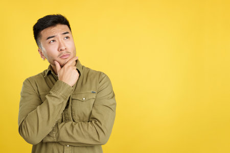 Chinese man with hand on face and thoughtful expressionの写真素材