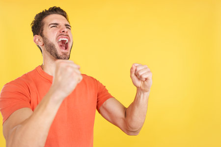 Excited caucasian man celebrating while raising armsの写真素材
