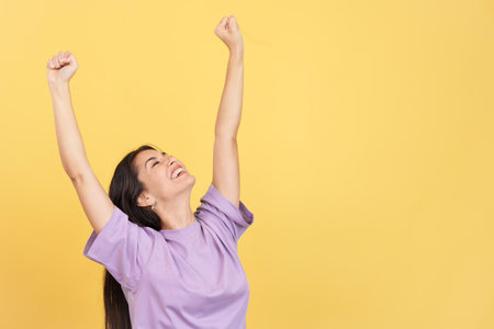 Happy caucasian woman celebrating while raising armsの写真素材