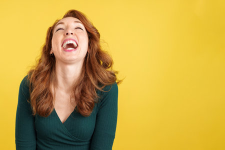 Happy redheaded woman laughing and looking upの写真素材