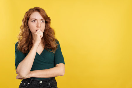 Redheaded woman with hand on face and thoughtful expressionの写真素材