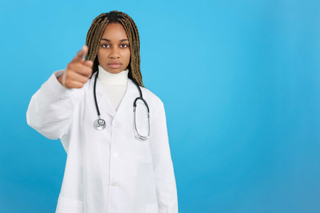 Serious African female doctor with uniform pointing forwardの写真素材