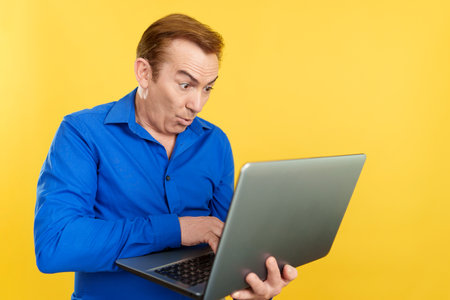 Mature man with a surprised look using a laptopの写真素材