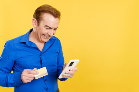 Mature man using the mobile and card to shopping onlineの写真素材
