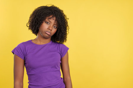 Sad woman with afro hair standing looking at cameraの写真素材