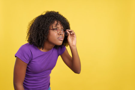 Woman with afro hair taking off her glasses to seeの写真素材