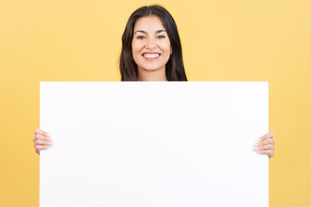 Woman holding a blank panel while smiling at the cameraの写真素材