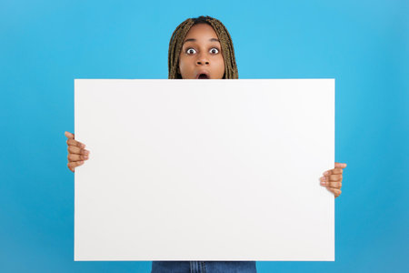 Surprised african woman holding a blank canvasの写真素材