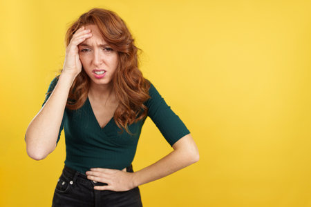 Redheaded woman gesturing bodily discomfort and headacheの写真素材