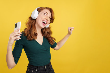 Cool redheaded woman listening to music with headphones and mobileの写真素材