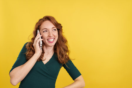 Happy redheaded woman talking to the mobileの写真素材