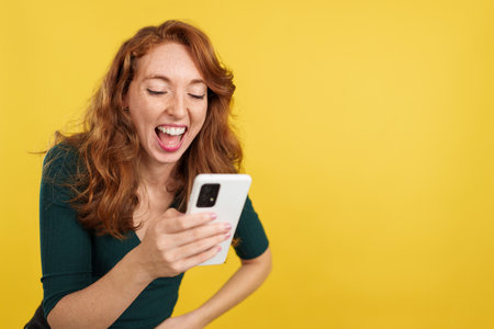 Redheaded woman laughing while using the mobile phoneの写真素材