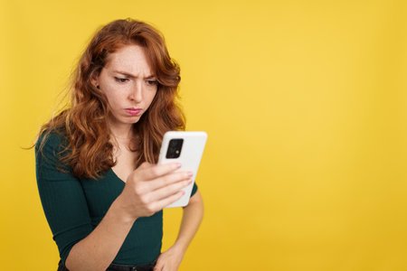 Worried redheaded woman using a mobile phoneの写真素材