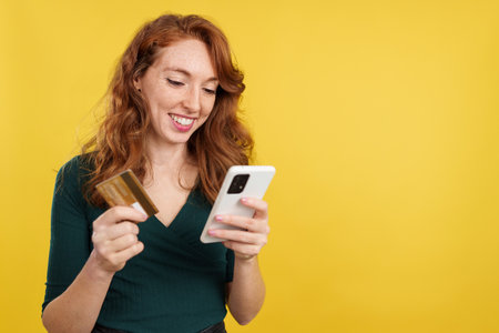 Happy redheaded woman shopping online with the mobileの写真素材